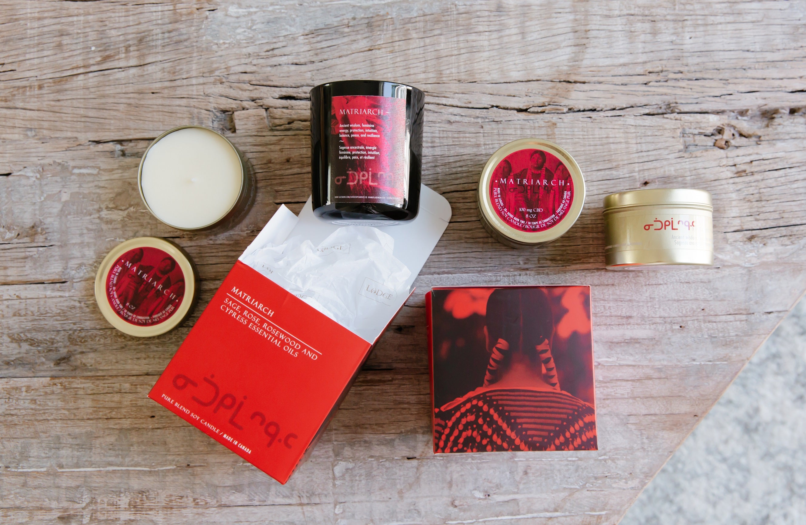 The 10oz Matriarch Candle and Gift Box on a wooden table, flat laid with the rest of the Matriarch collection.